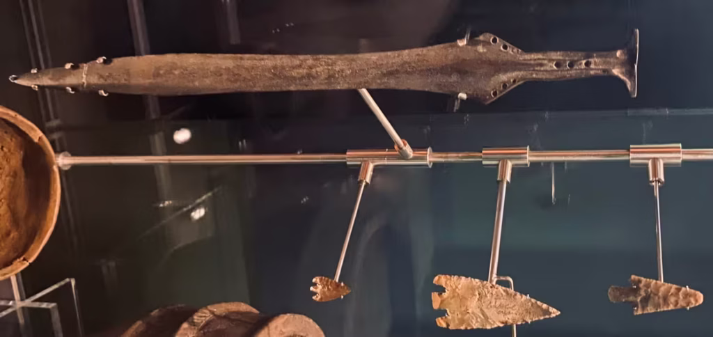 Photograph of Bronze Age artifacts on display at the Braid Museum in Ballymena. These include a sword found near Ballymoney, and flint barbed arrowheads discovered at various locations in Northern Ireland.